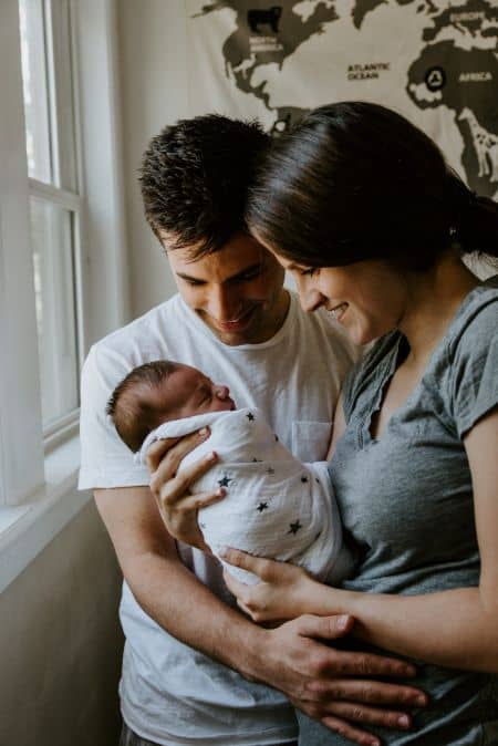 Newborn baby being held by smiling parents.