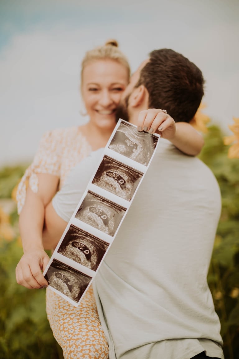Smiling couple embracing with scan picture